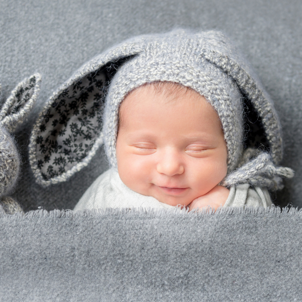 Маленький грудной ребенок в серой шапке с ушками