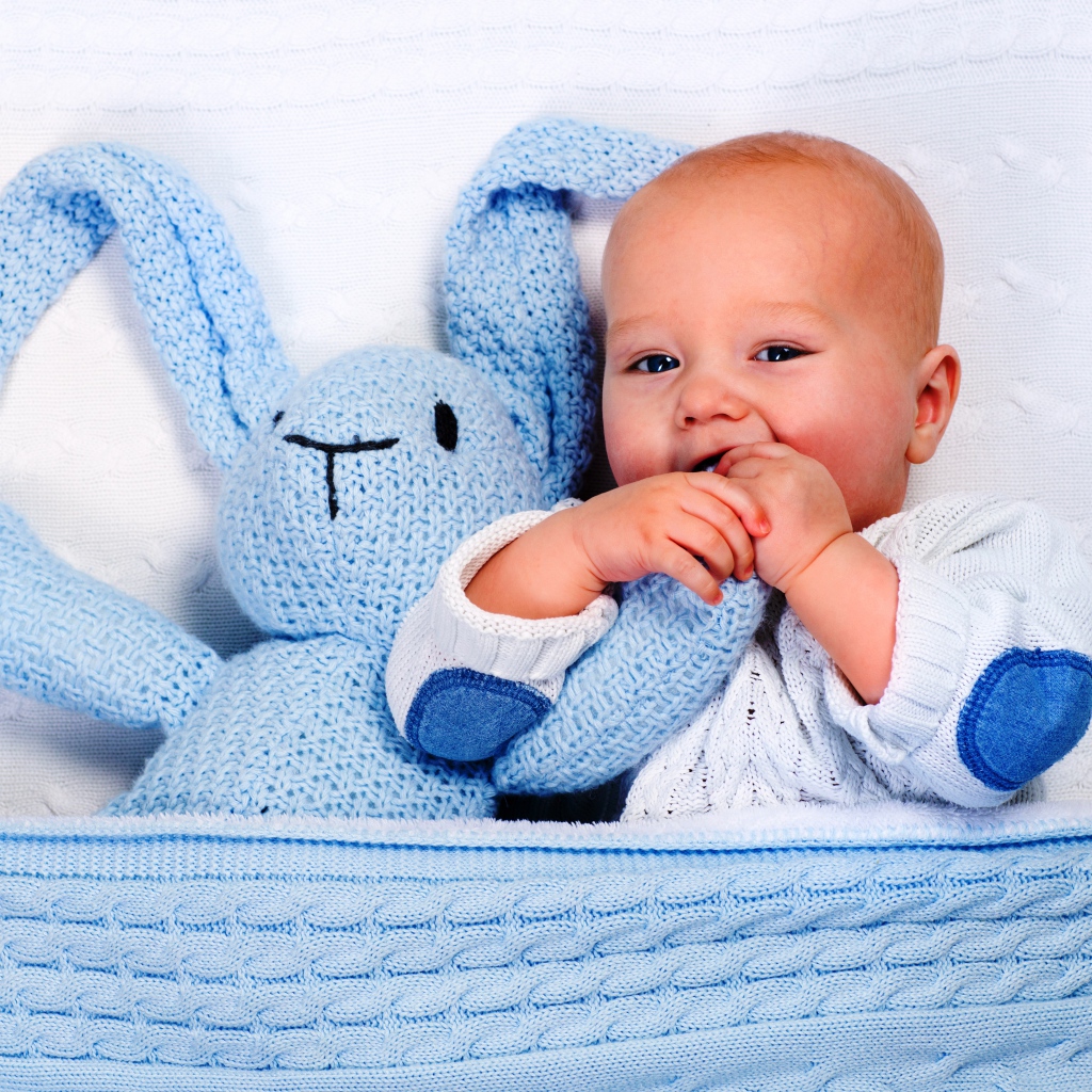 Маленький грудной ребенок грызет мягкую игрушку 