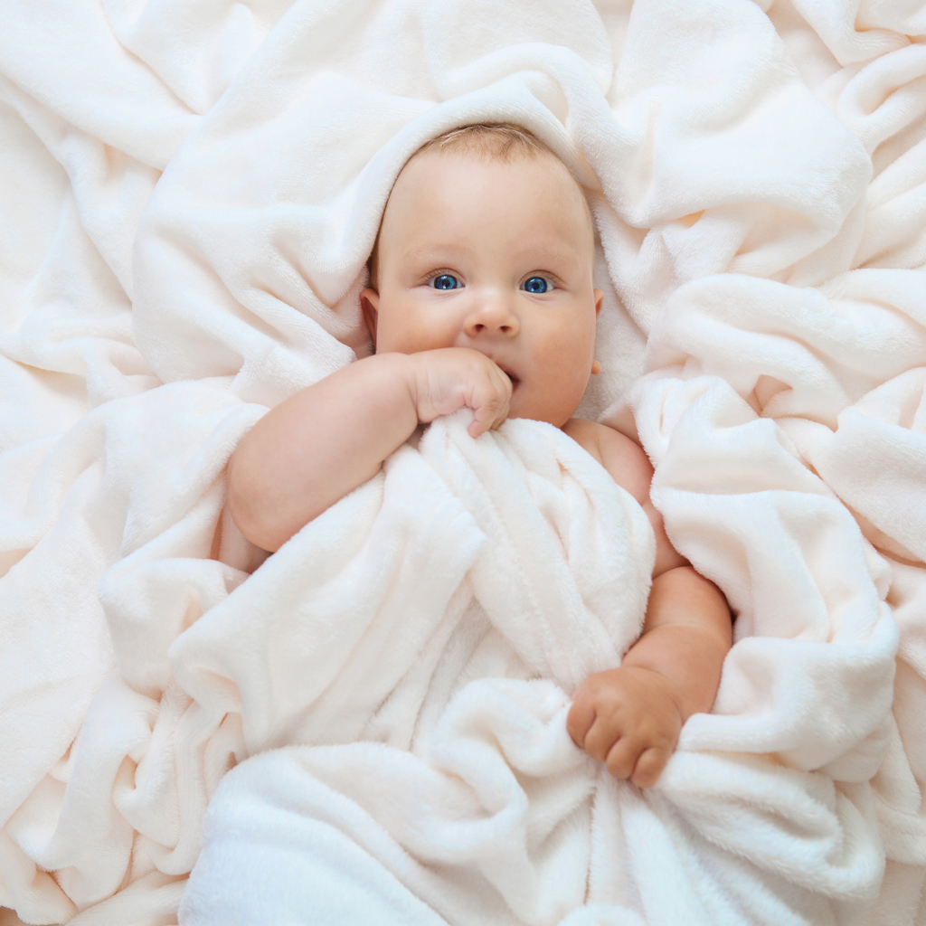 Маленький голубоглазый ребенок в покрывале 