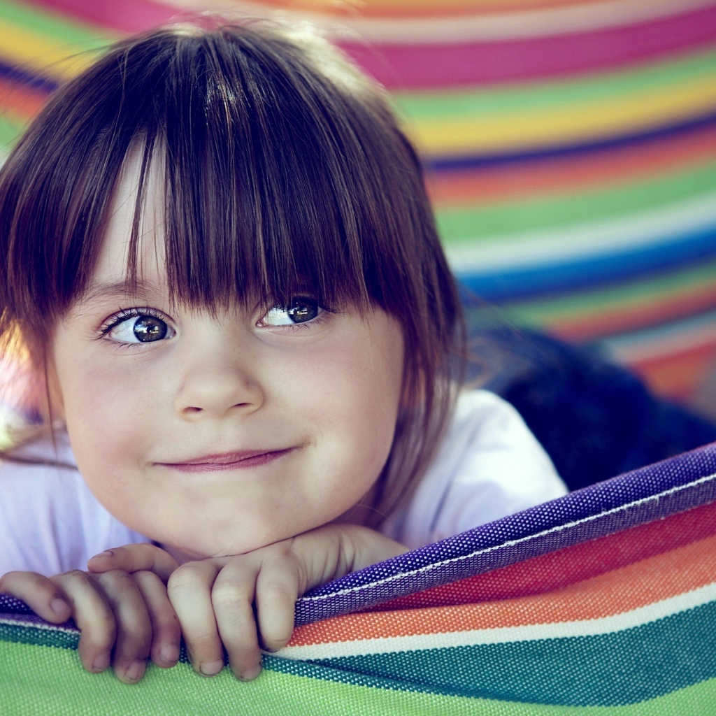 Маленькая кареглазая девочка лежит в гамаке