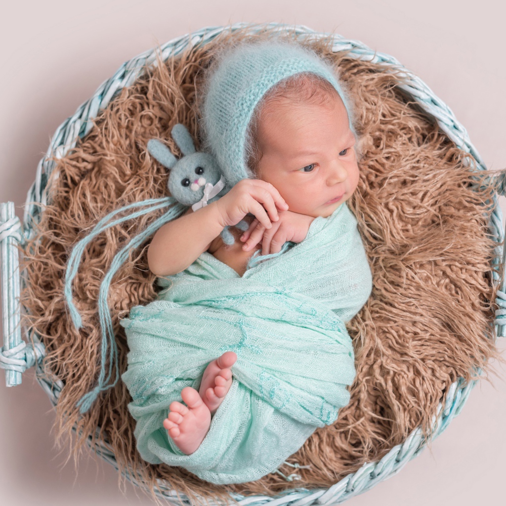 Маленький ребенок в корзине на сером фоне