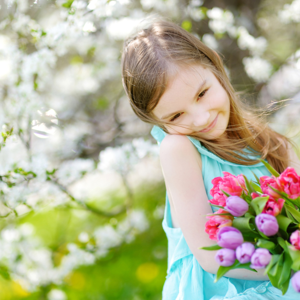 Beautiful little girl with a bouquet of tulips in the spring