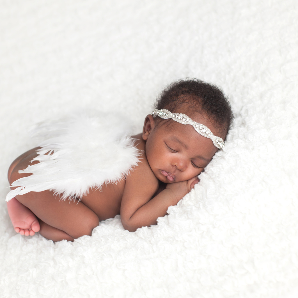 Темнокожий младенец спит с крыльями ангела