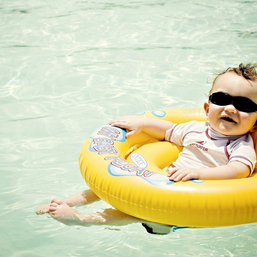 Веселый малыш на спасательном кругу в бассейне