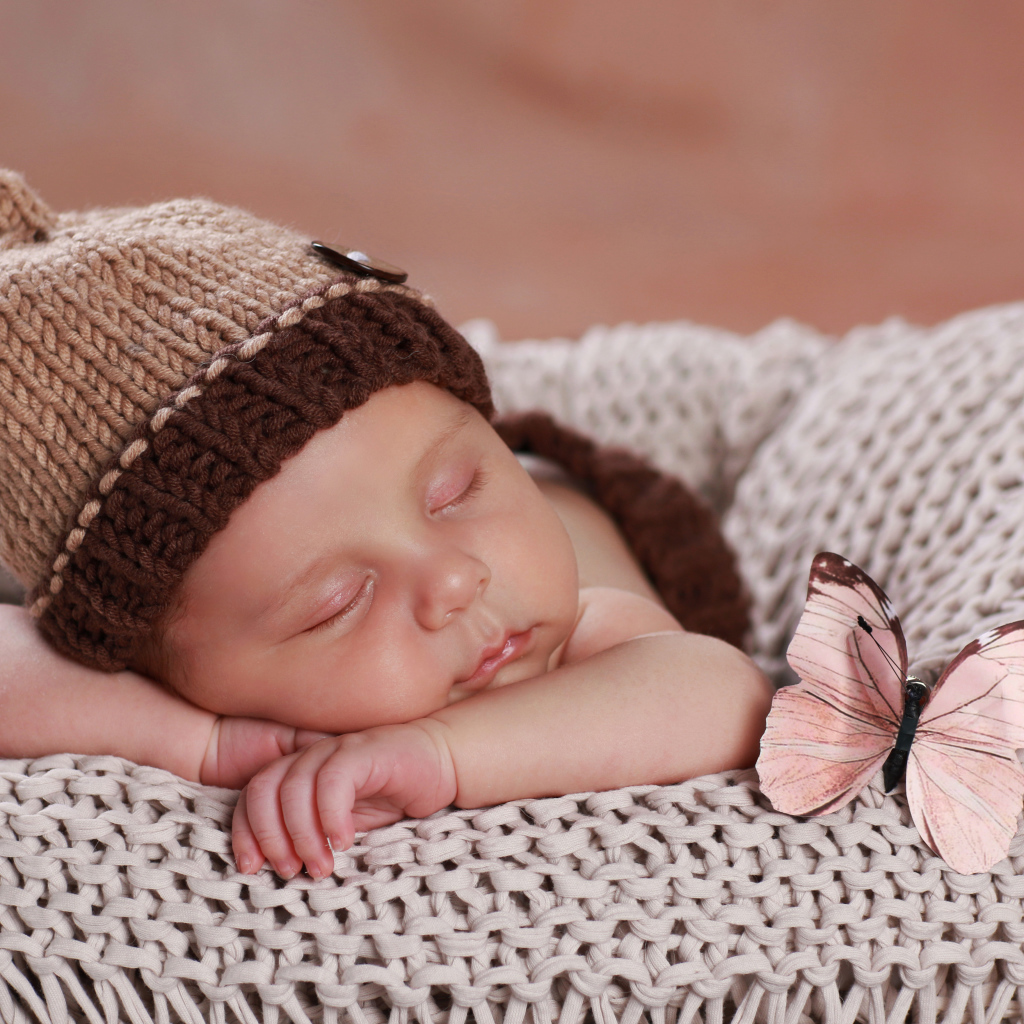 Милый спящий ребенок в коричневой вязаной шапке 