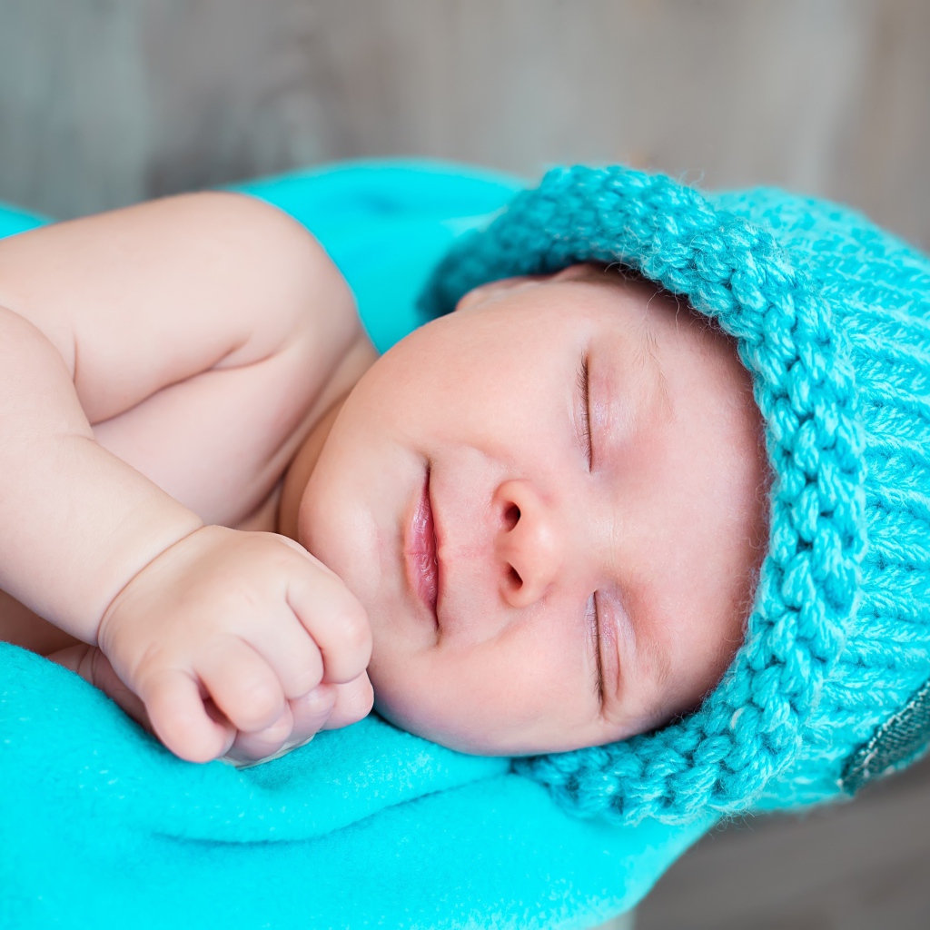 Милый спящий ребенок в голубой вязаной шапке