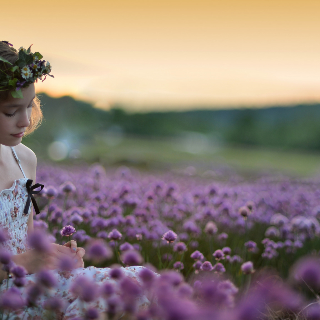 Нежная маленькая девочка сидит на поле с сиреневыми цветами