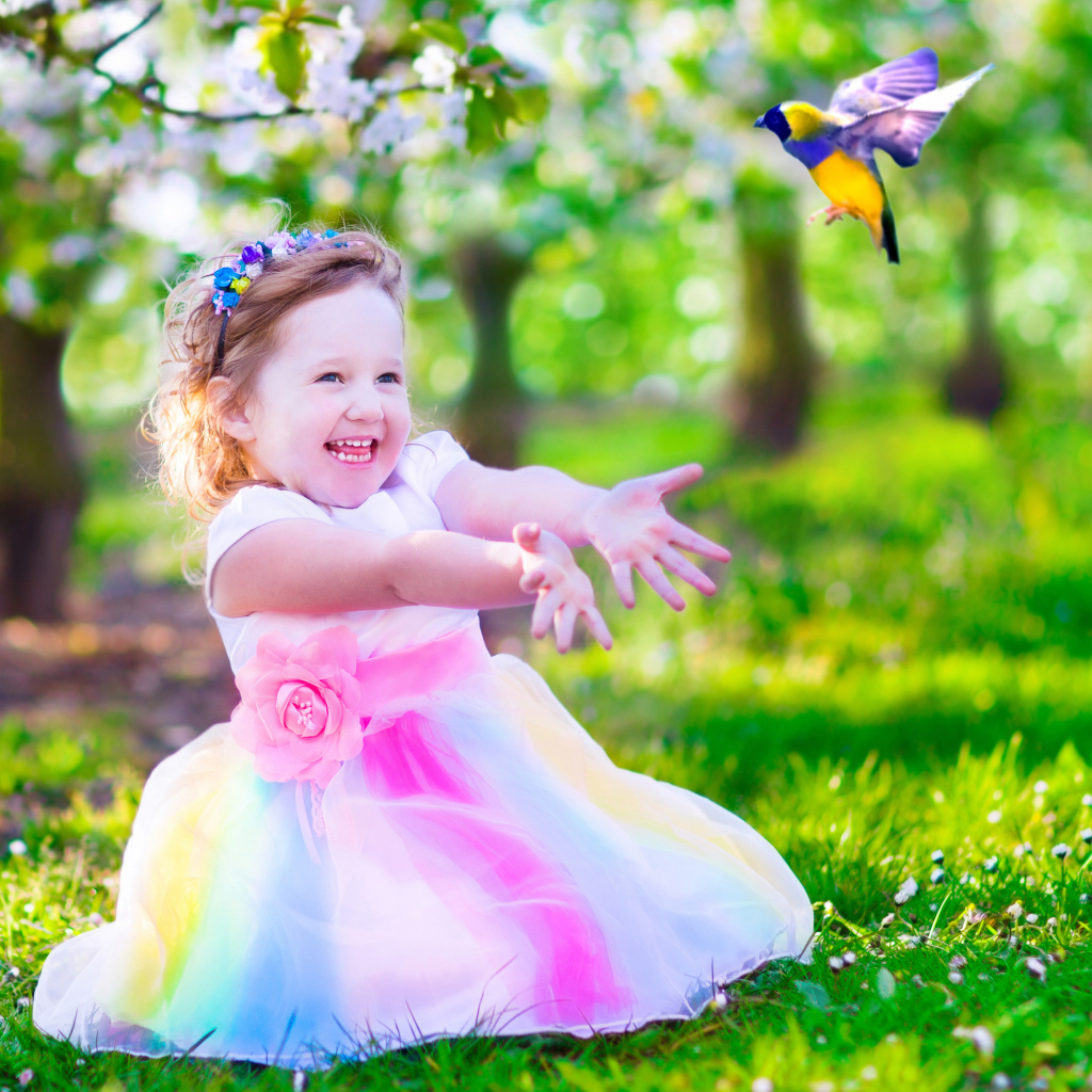 Смеющаяся маленькая девочка в красивом платье на зеленой траве