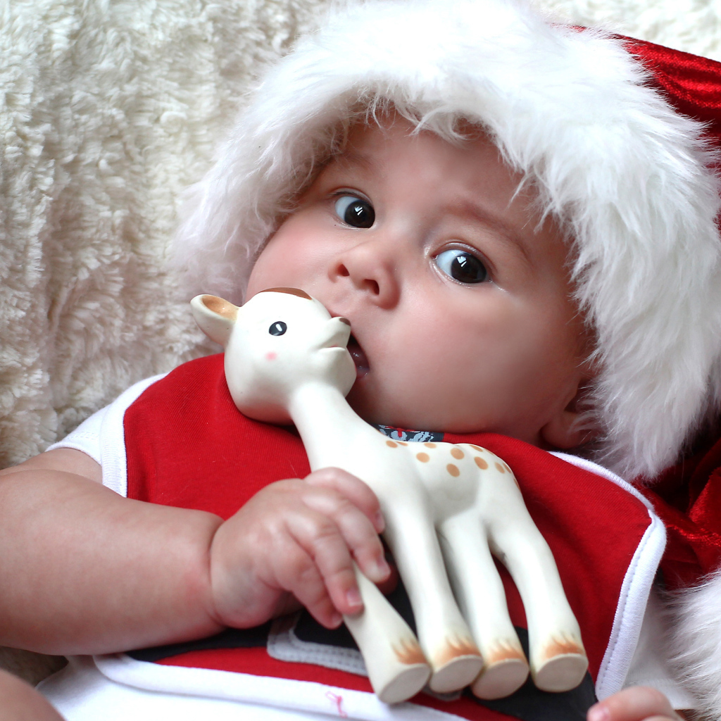 Маленький ребенок в новогодней шапке с игрушкой в руке