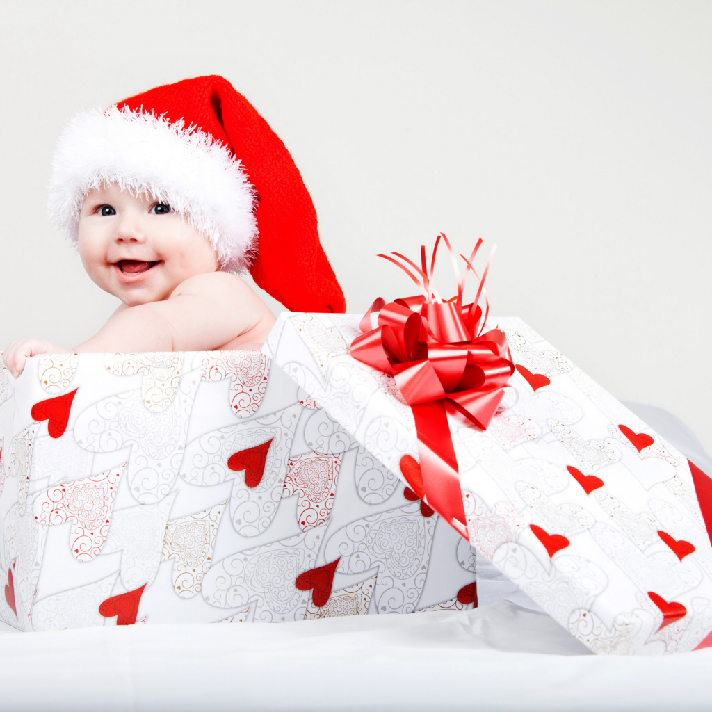 Маленький ребенок в новогоднем костюме в коробке для подарка на сером фоне