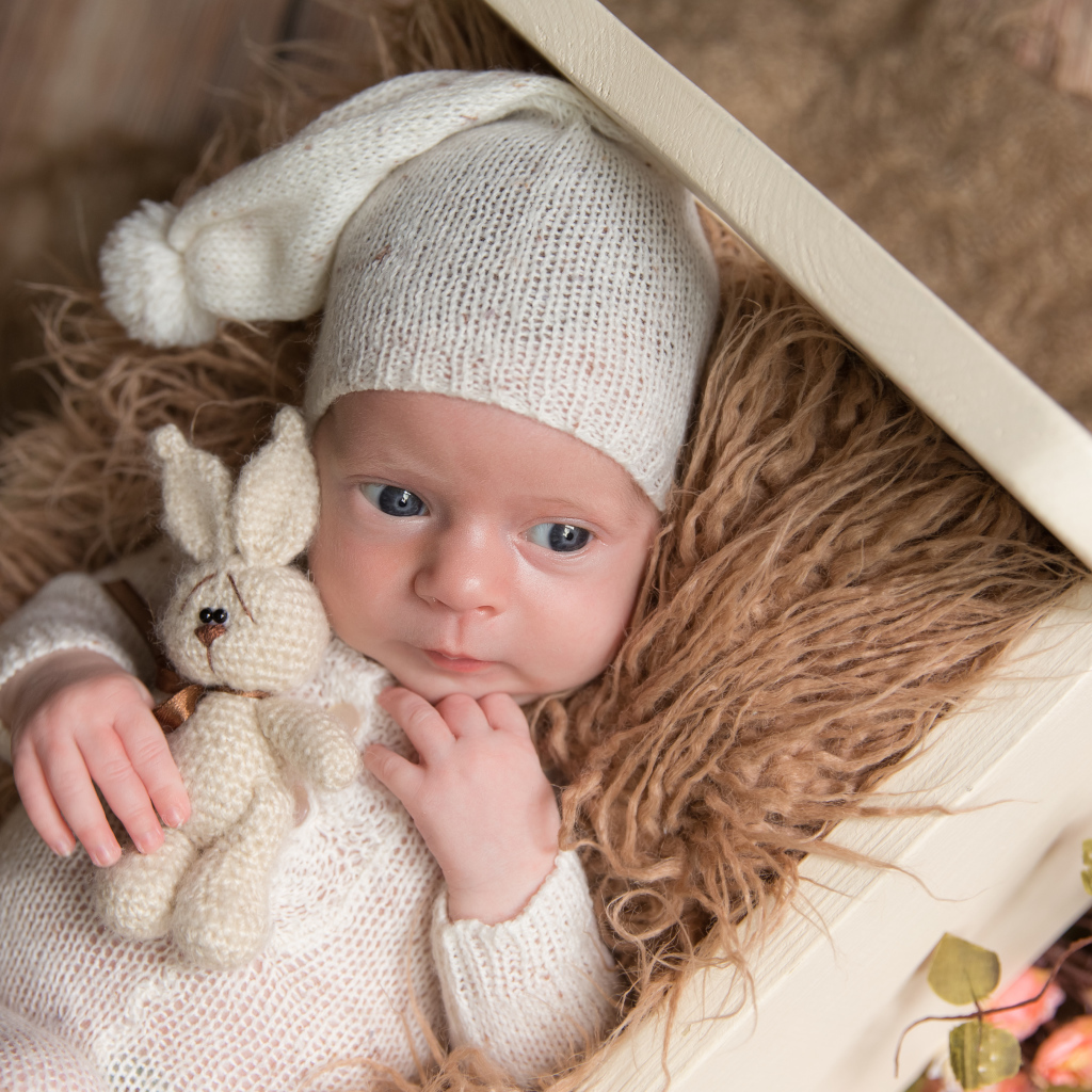 Маленький ребенок в вязанном костюме с зайчиком