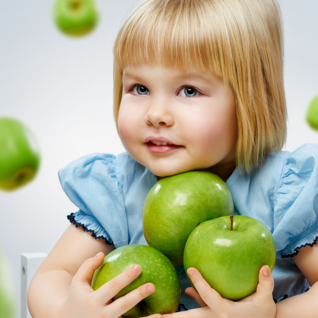 Маленькая девочка блондинка с зелеными яблоками