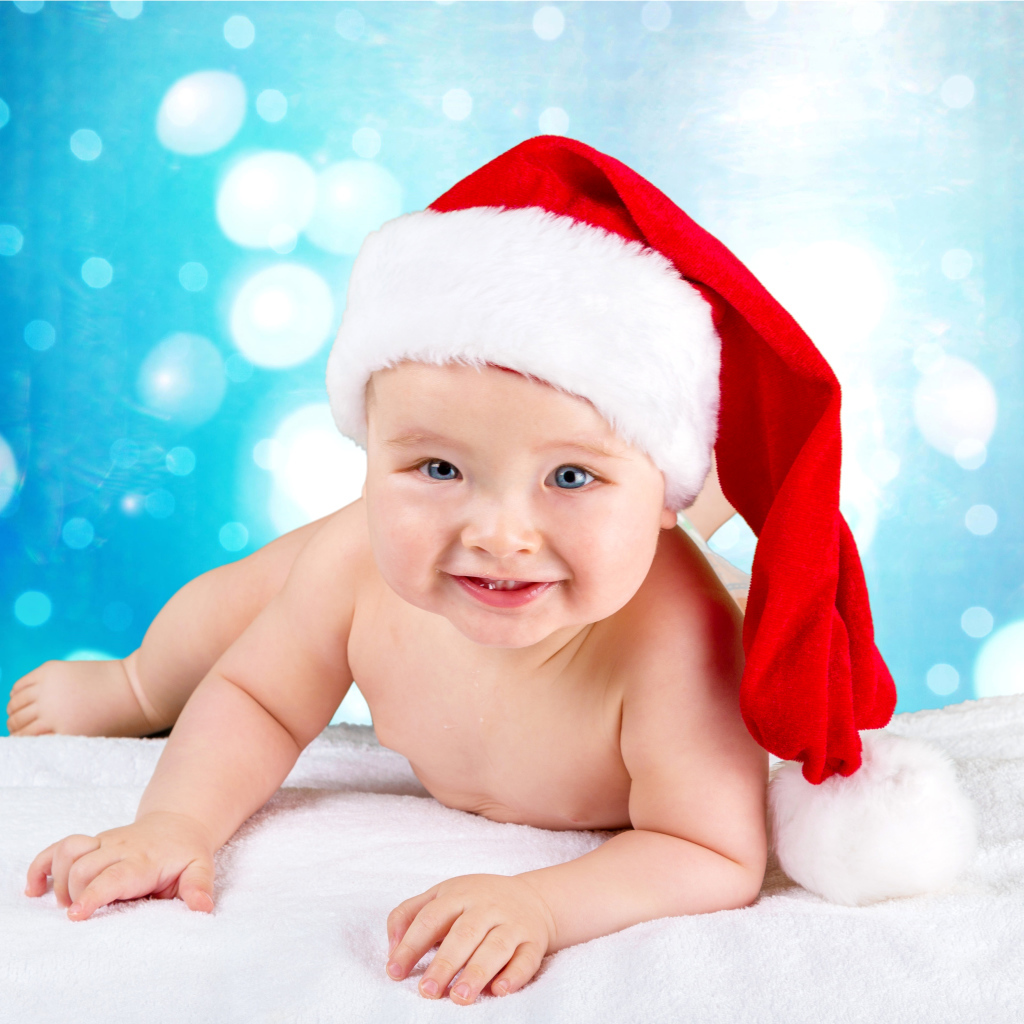 Маленький голубоглазый ребенок в красном новогоднем колпаке