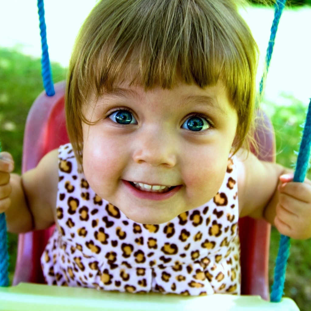 Маленькая голубоглазая девочка на качели