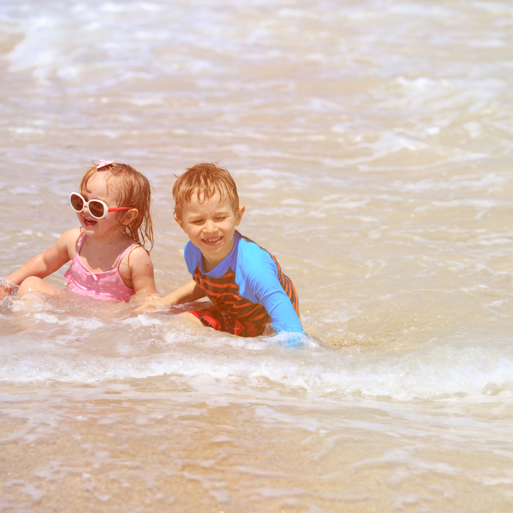 Маленькие мальчик и девочка купаются в море 