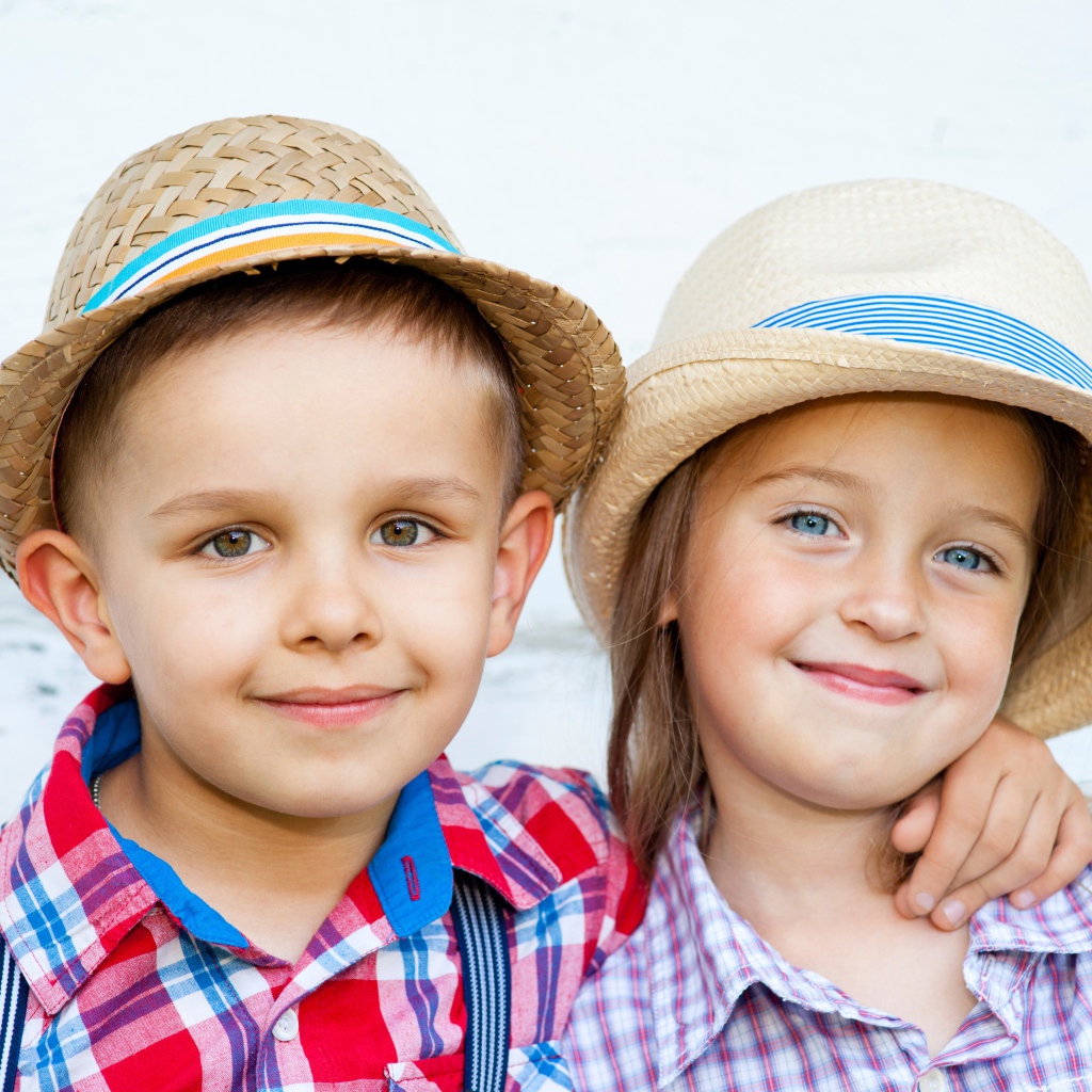 Маленькие мальчик и девочка в соломенных шляпах на пляже