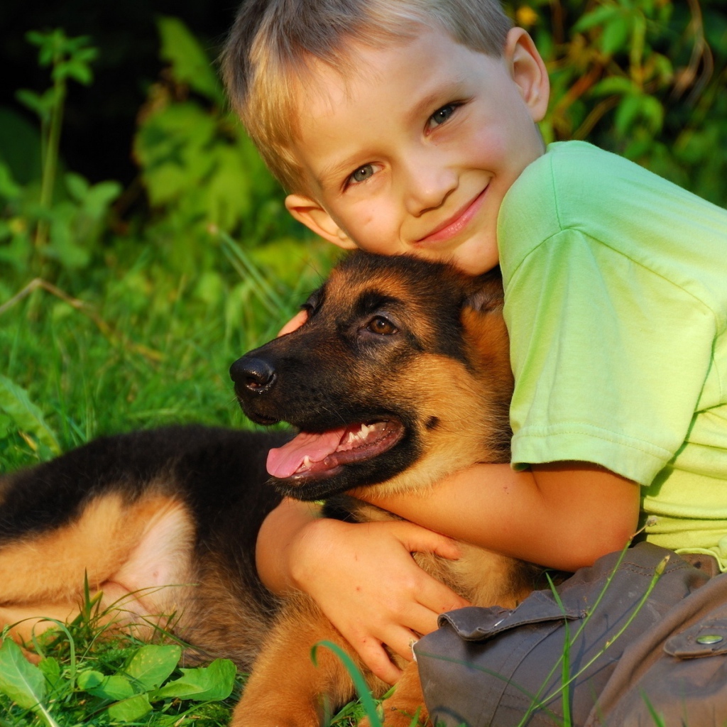 Маленький мальчик обнимает щенка немецкой овчарки