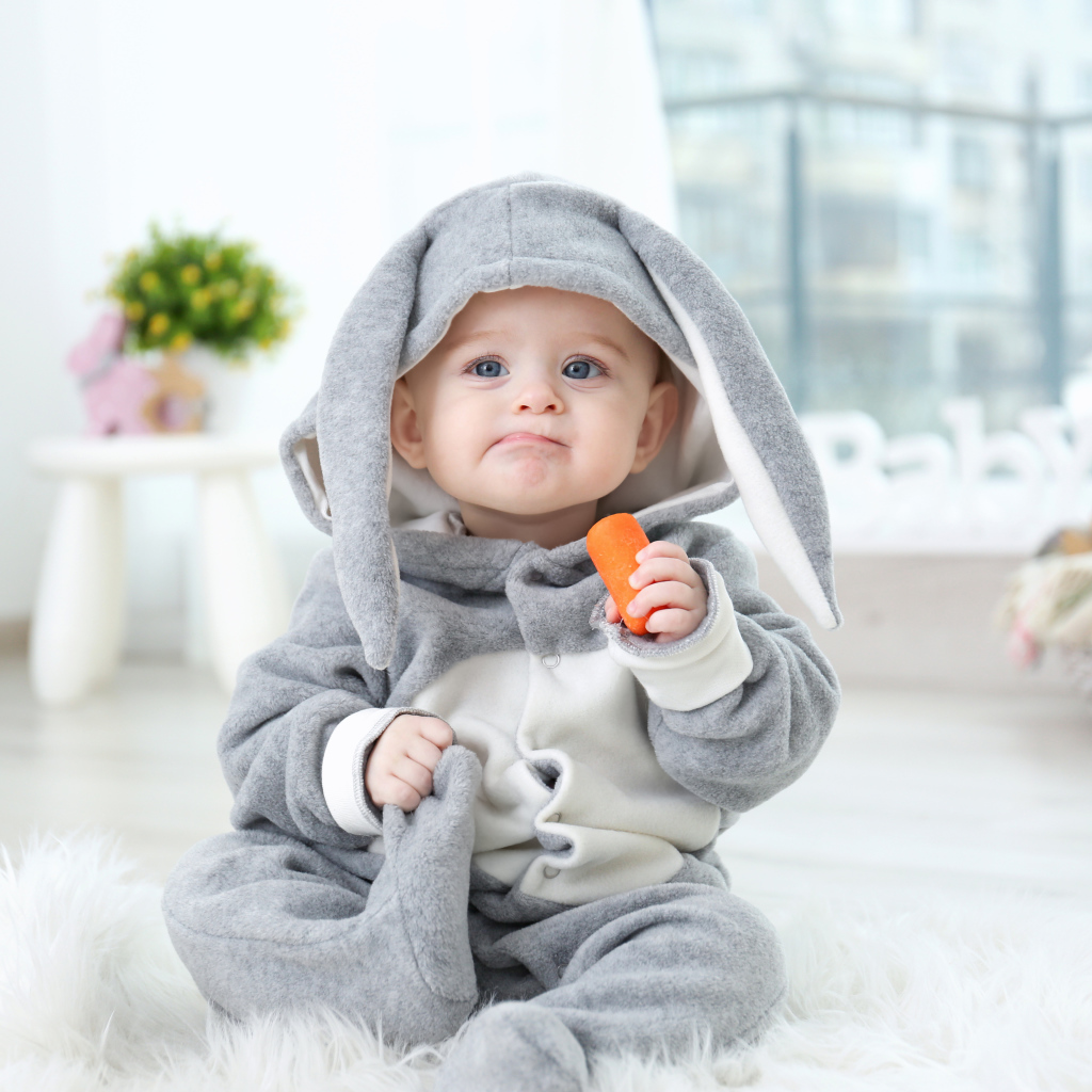 Маленький мальчик в костюме зайчика с морковкой в руке