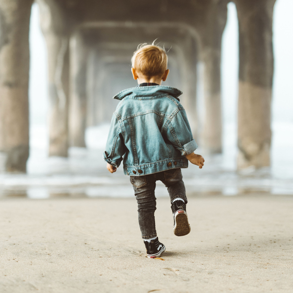 Маленький мальчик в джинсовой куртке спиной