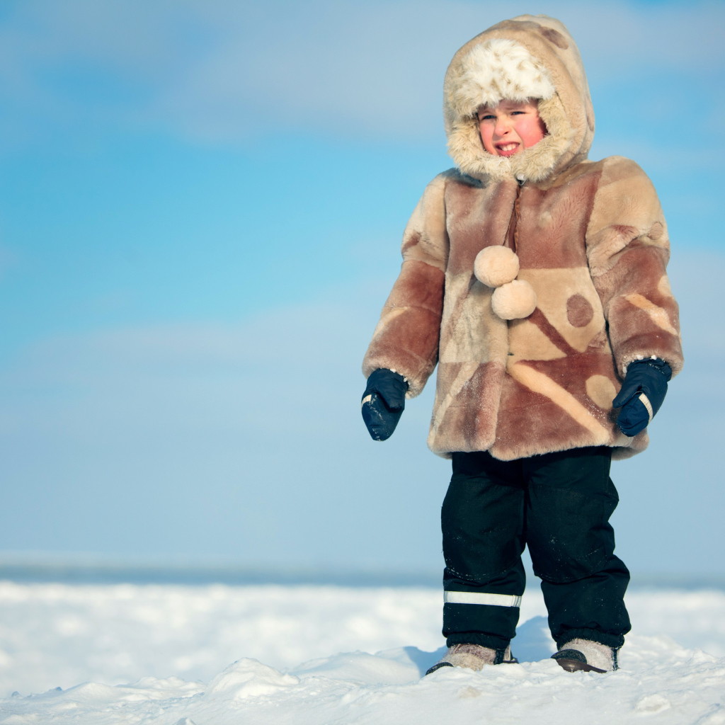 Маленький мальчик в теплой шубе на снегу 