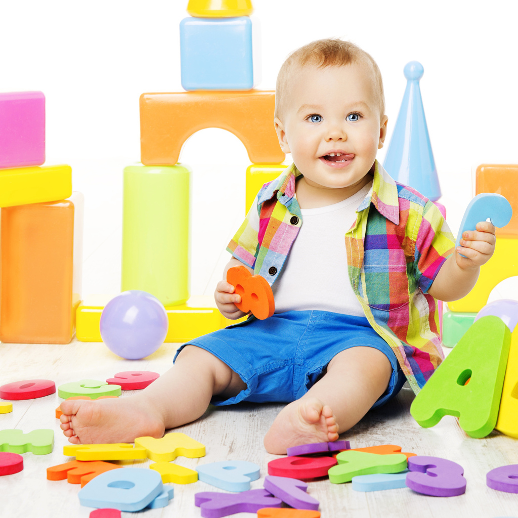 Маленький мальчик играет с разноцветными игрушками 