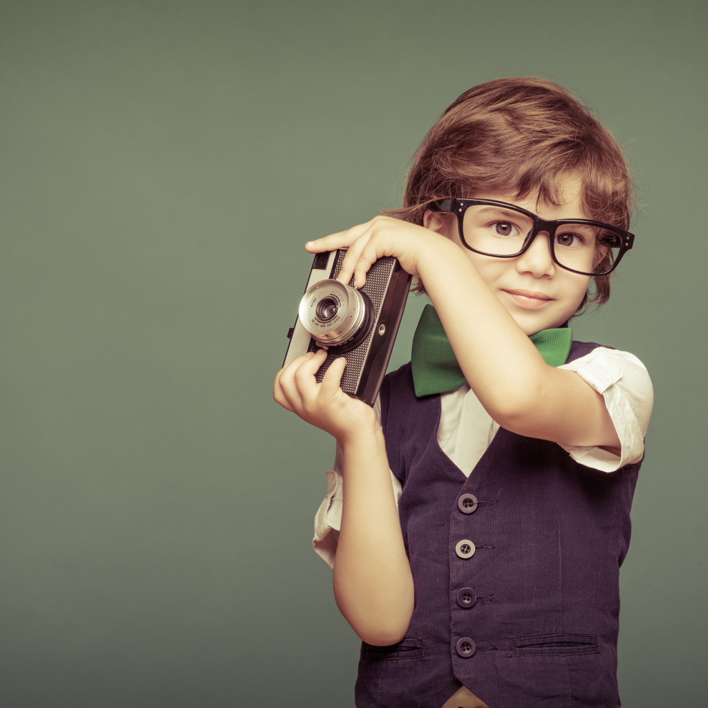 Маленький мальчик в очках с фотоаппаратом
