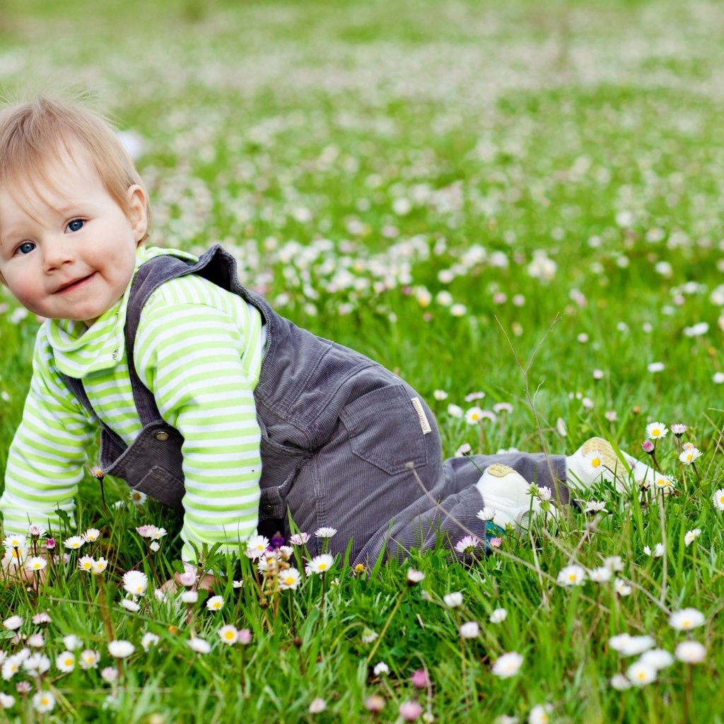 Маленький веселый мальчик на поляне с белыми цветами