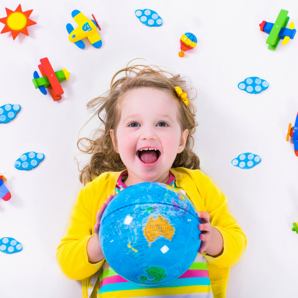 Маленькая веселая девочка с глобусом в руках 