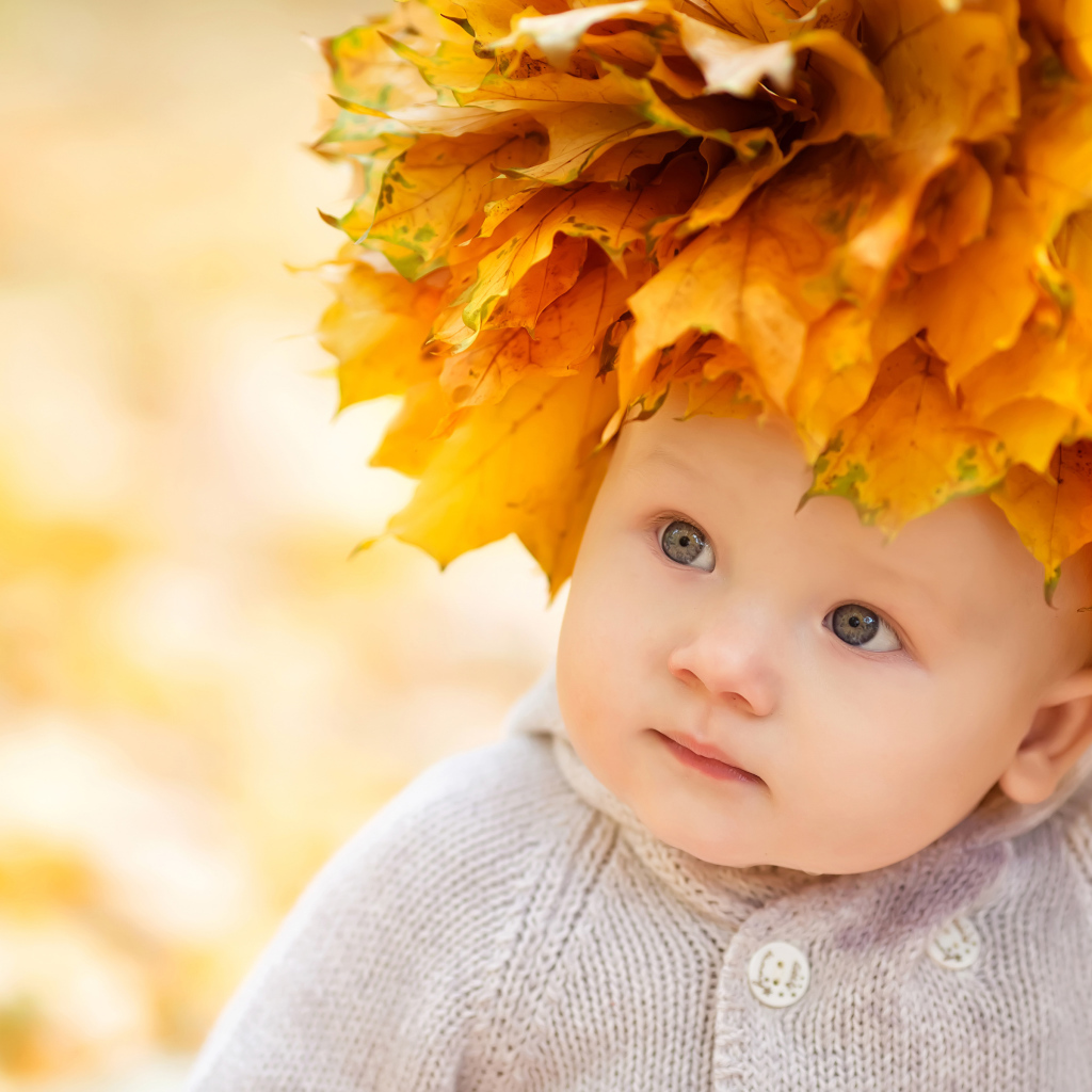 Маленький милый ребенок с венком из желтых листьев на голове 