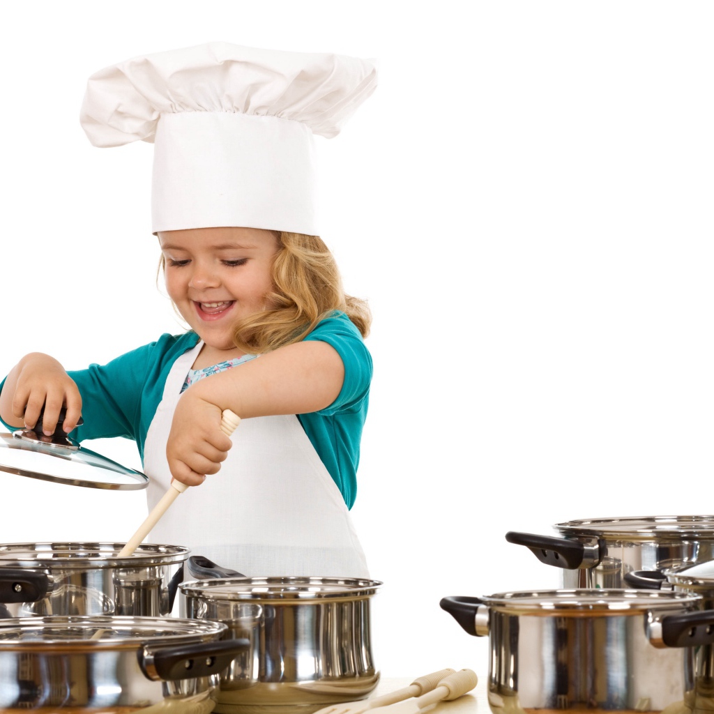 Маленькая девочка в костюме повара на кухне