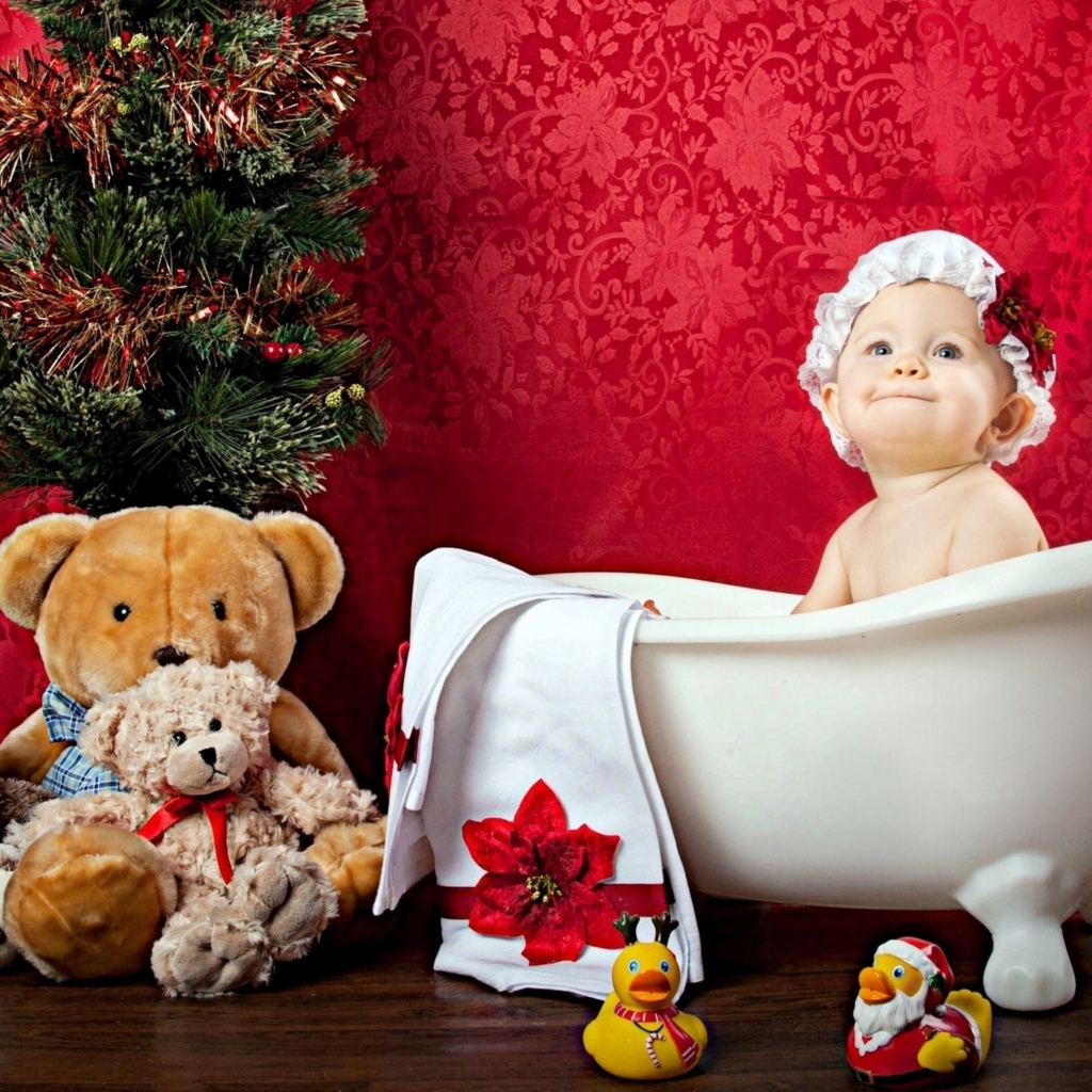 Маленькая девочка сидит в белой ванне у елки с игрушками