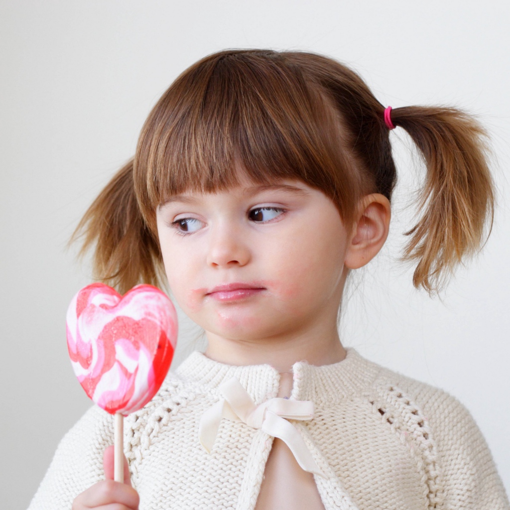 Маленькая девочка с большой конфетой на палочке