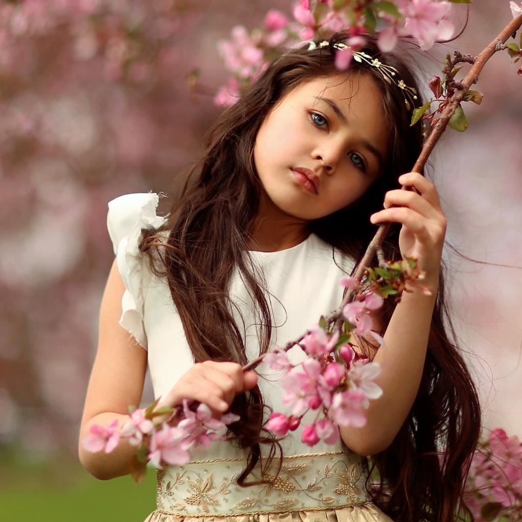 Маленькая девочка у цветущей розовыми цветами ветки