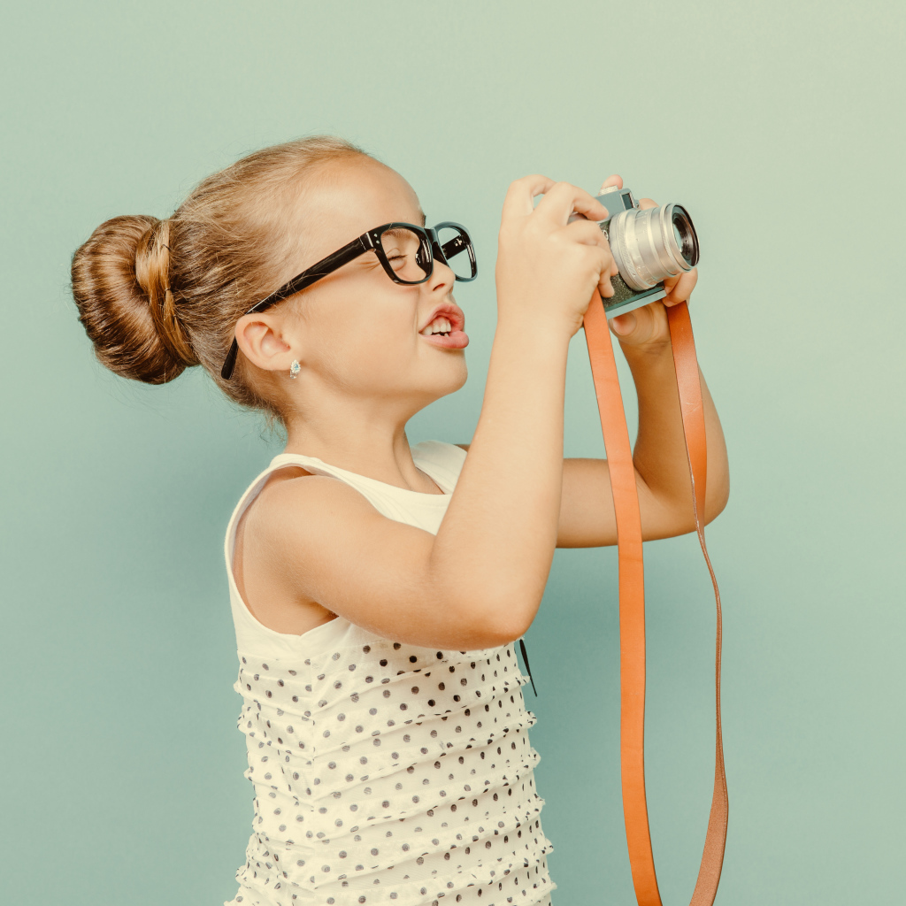 Маленькая девочка в очках с фотоаппаратом