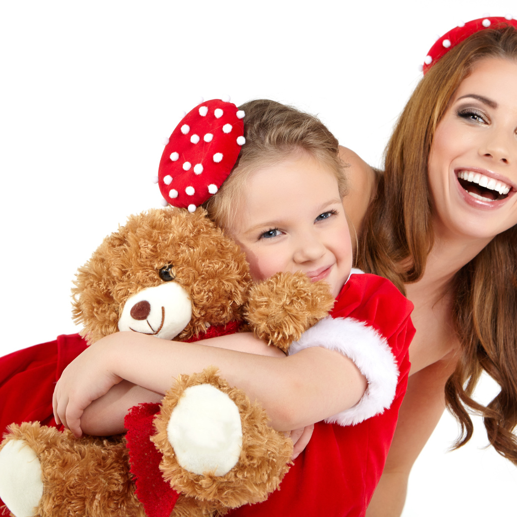Маленькая девочка с мамой обнимает игрушечного медвежонка