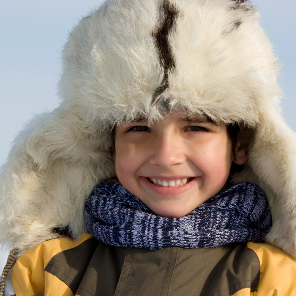 Маленький улыбающийся мальчик в теплой шапке зимой