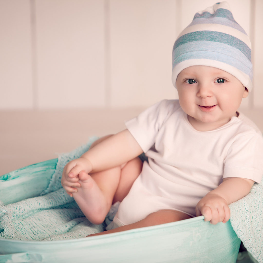 Маленький улыбающийся ребенок сидит в железном тазике