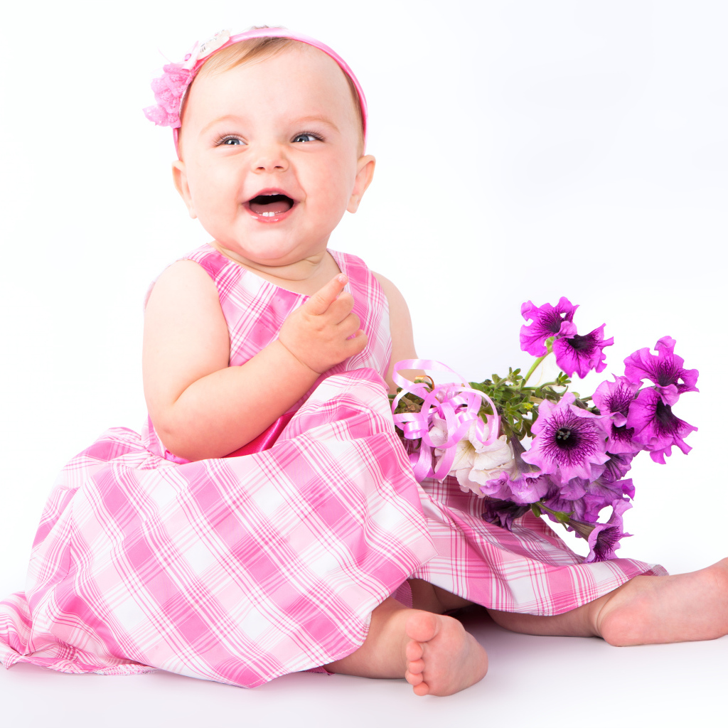 Маленькая улыбающаяся девочка с букетом петунии на белом фоне