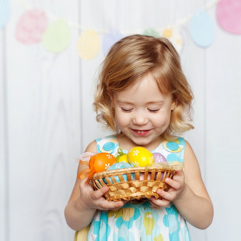 Маленькая улыбающаяся девочка с пасхальными яйцами в руках