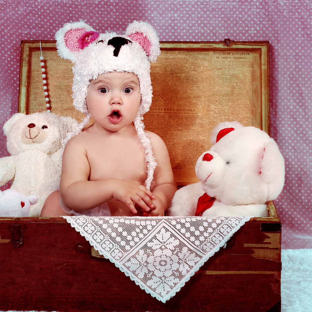 Маленький удивленный ребенок сидит в чемодане с игрушками