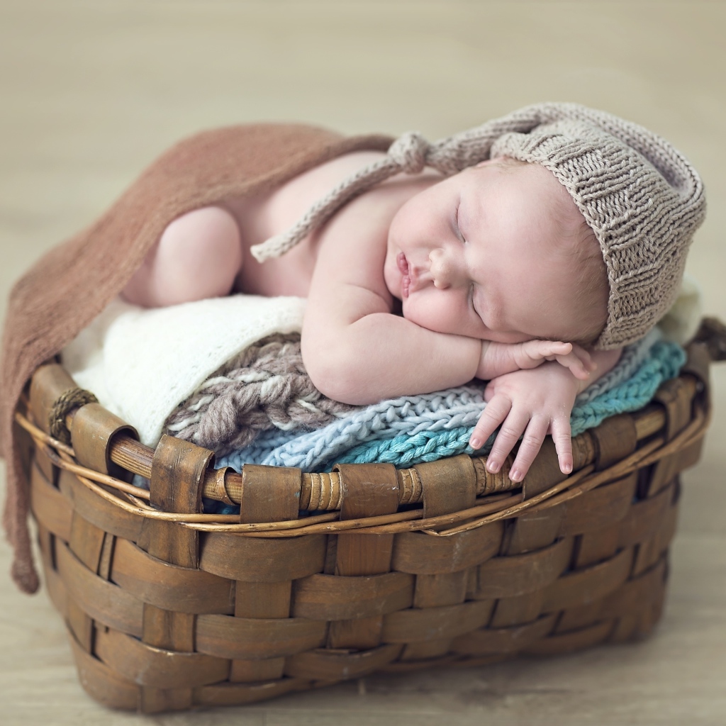 Спящий грудной ребенок в шапке в корзине 