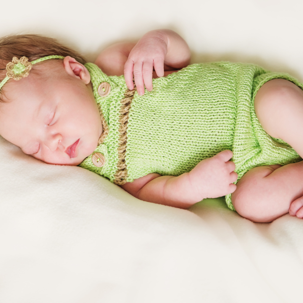 Спящий младенец в вязаной одежде