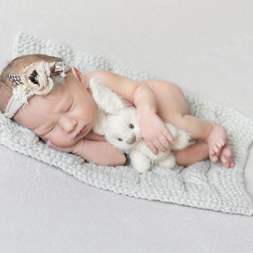 Спящий грудной ребенок с вязаной игрушкой