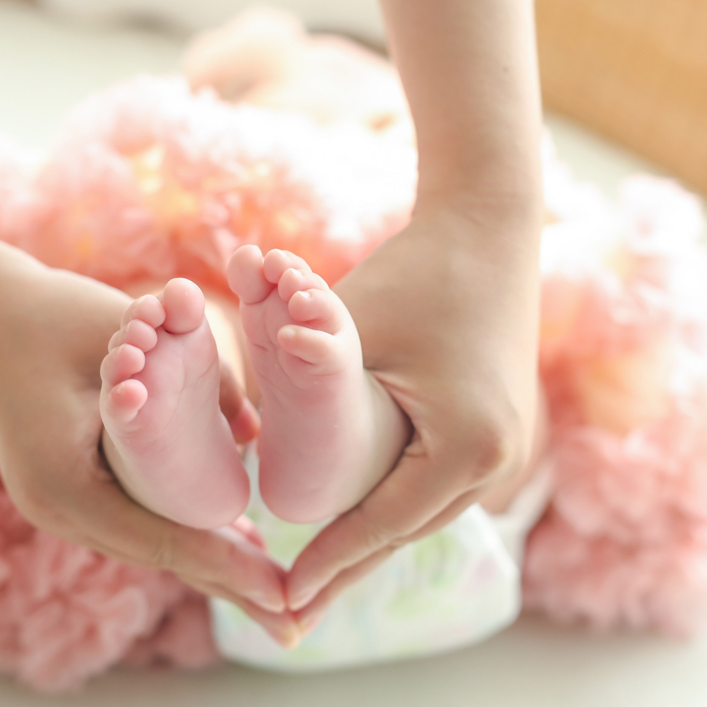 Маленькие ножки новорожденного в ладонях у мамы 