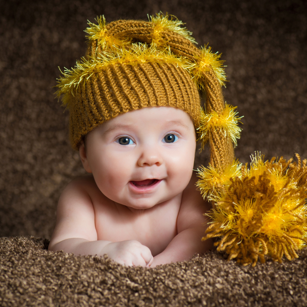 Улыбающийся малыш в красивой вязанной шапке 