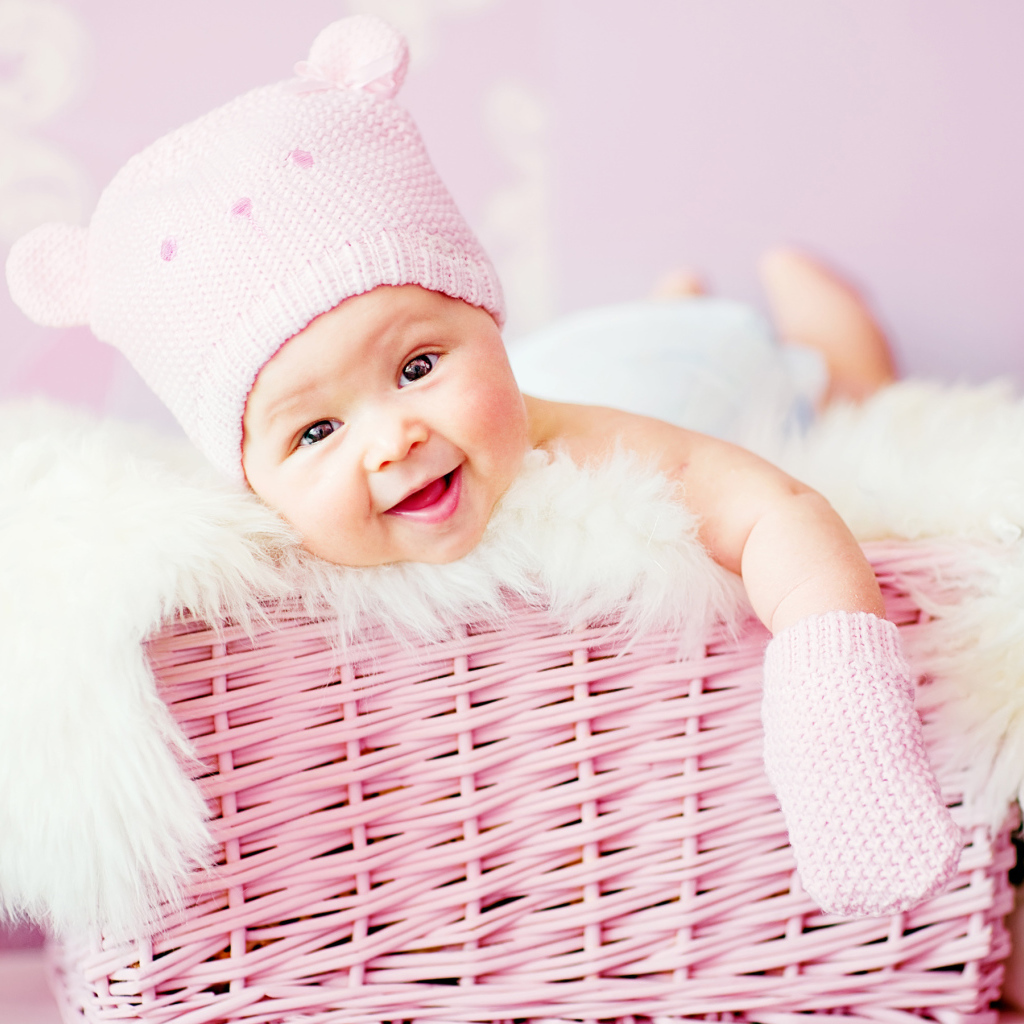 Улыбающийся грудной ребенок лежит в розовой корзине