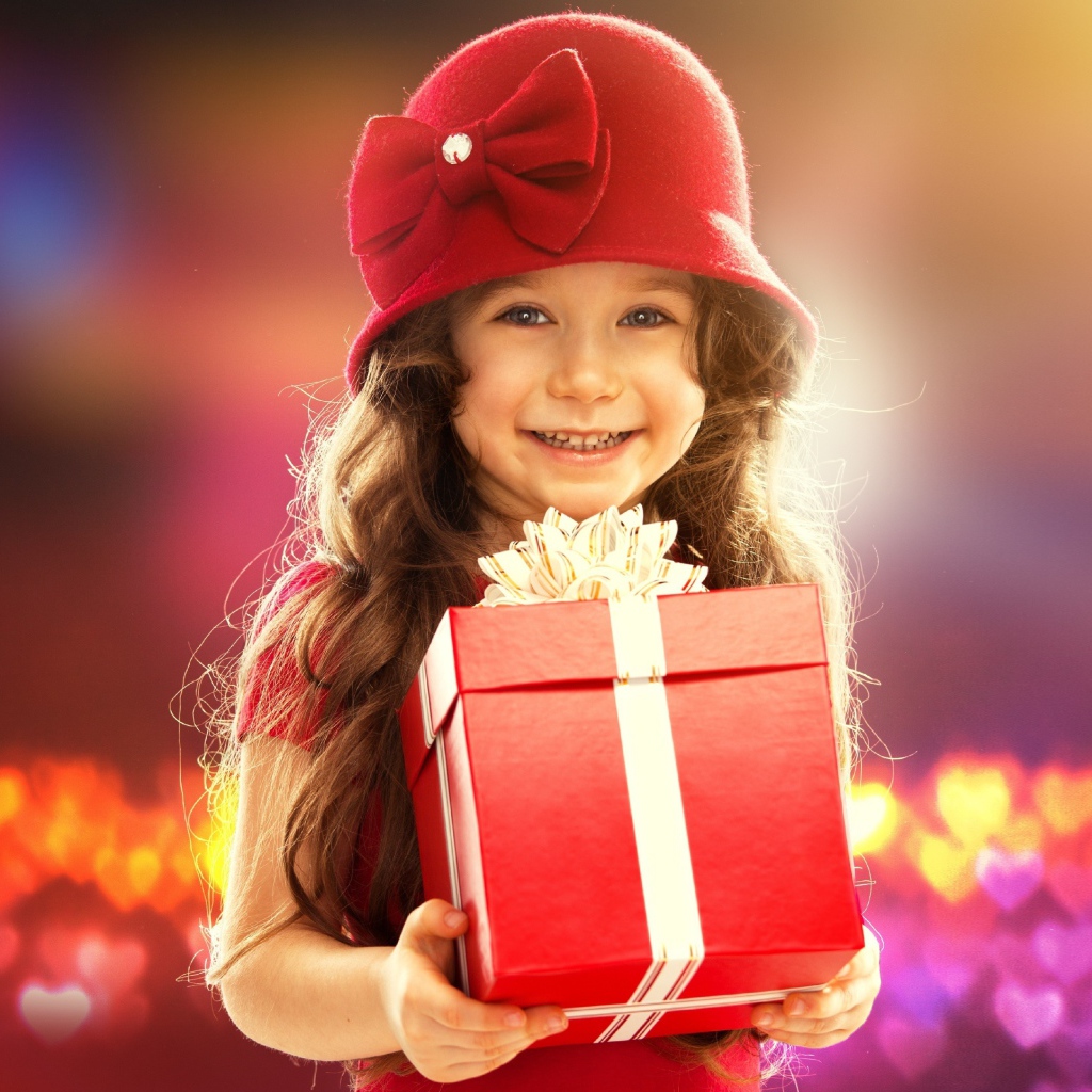 Улыбающаяся голубоглазая девочка с большим подарком в руках