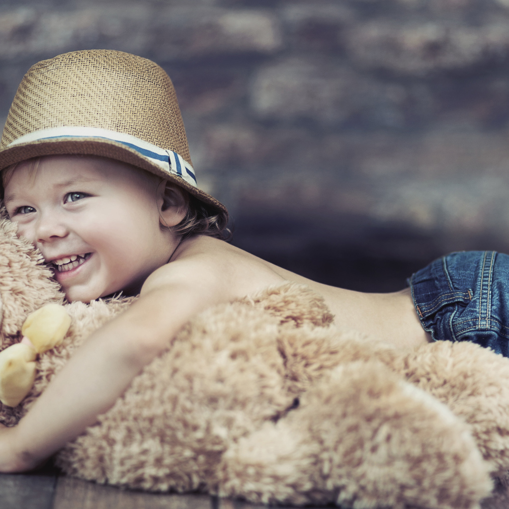 Улыбающийся мальчик обнимает игрушку