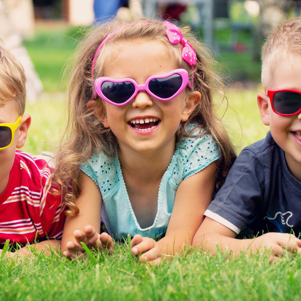 Улыбающиеся мальчики и девочка лежат на зеленой траве