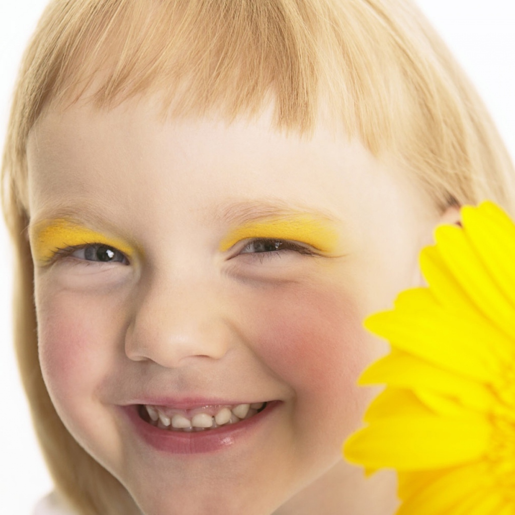 Улыбающаяся девочка с желтым цветком герберы